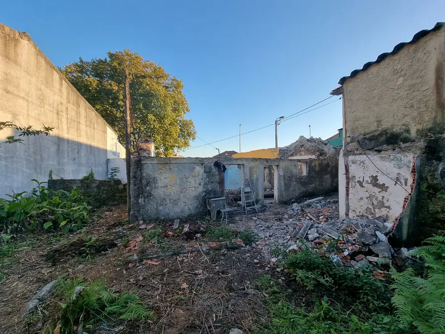 Construction: street view during demolition showing exposed granite masonry walls stripped of render, through doorway pink interior plaster visible, revealing building archaeology layers