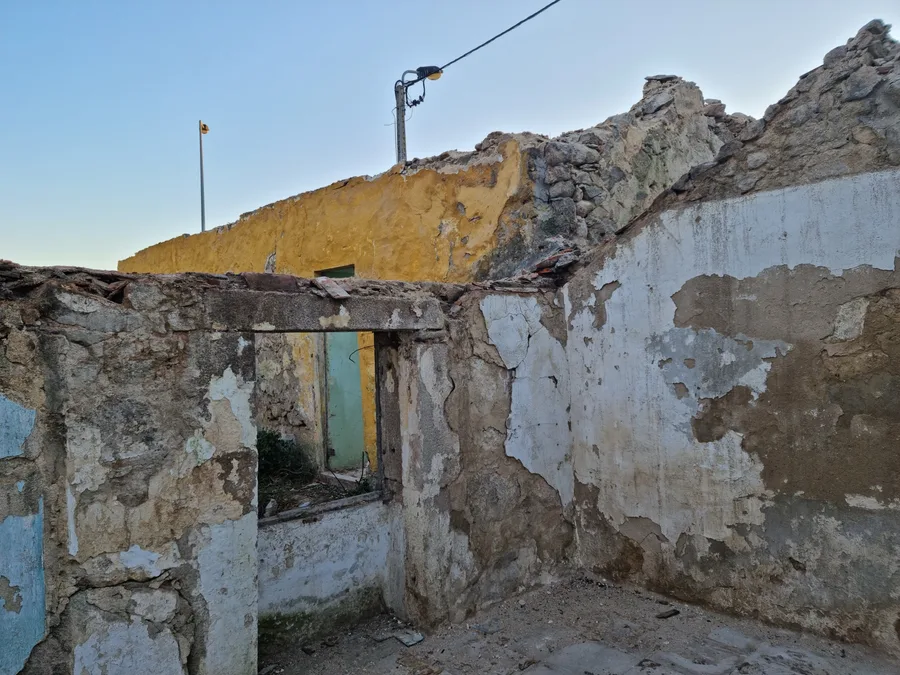 Construction: first demolition phase photo with entire roof removed showing interior exposed to sky, granite stone walls standing, and building stripped back to structural bones