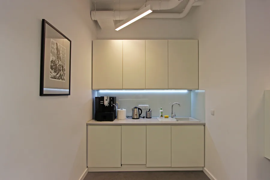 Interior detail showing the integration of warm natural wood surfaces with the restrained white office palette and woven vinyl flooring