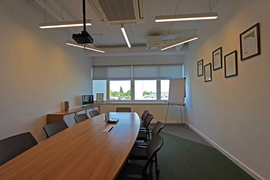Director private office viewed through glass partition with iMac workstation, white desk with natural wood top, and the restrained white-on-white aesthetic