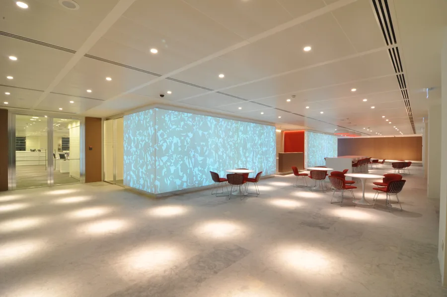 Wide view of bar and cafe zone with Corian panels glowing blue, revealing how the panels form a freestanding architectural volume