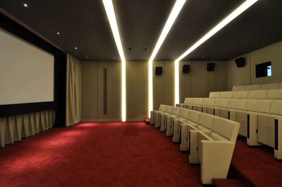 Screening room showing the cinema screen, tiered seating with Walt Disney-embossed leather seats, and surround sound system