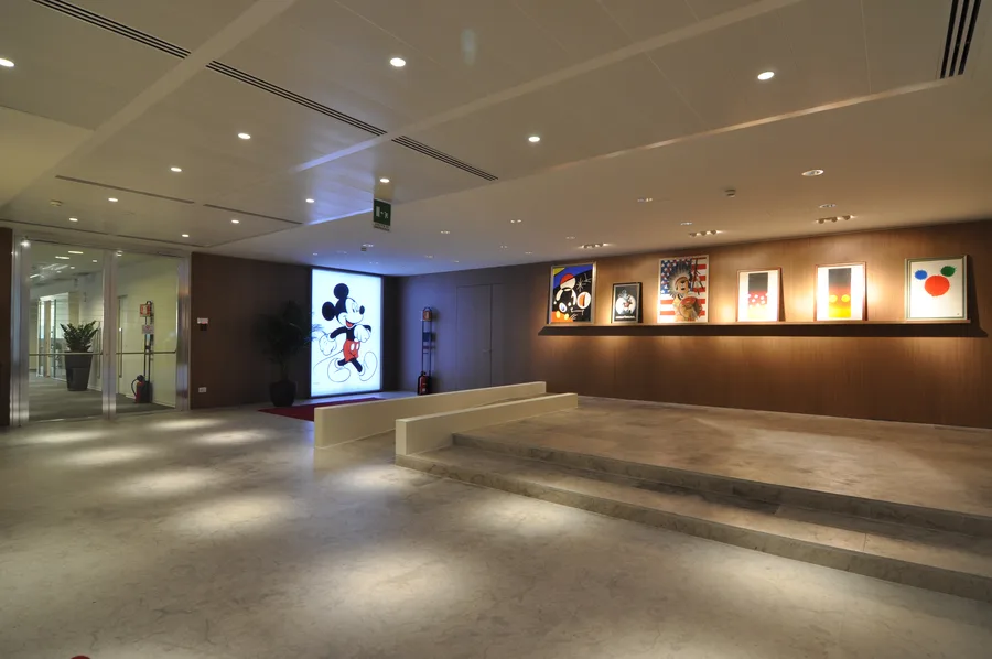 Wider art gallery view showing the full corridor with Disney prints, Grey Oak panelling, and warm downlighting along the display wall