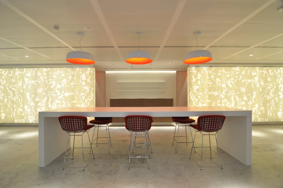 Symmetrical bar composition with three Artemide Skydro pendants above, four Bertoia stools below, and Corian relief panels behind