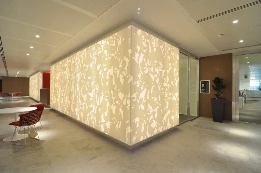 Corian architectural volume glowing from within, the laser-cut Disney-motif panels creating patterned light on surrounding floor and walls