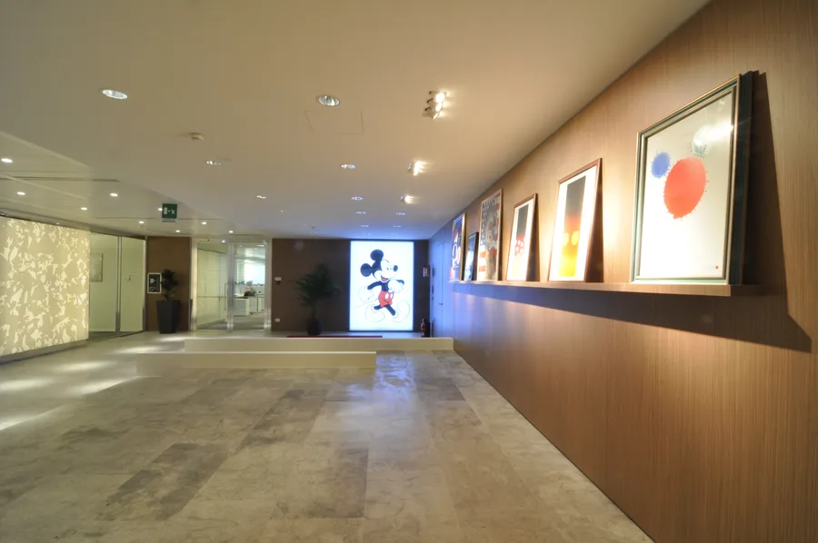 Art gallery with Grey Oak veneer wall and Disney artwork display, warm spotlighting creating intimate gallery atmosphere