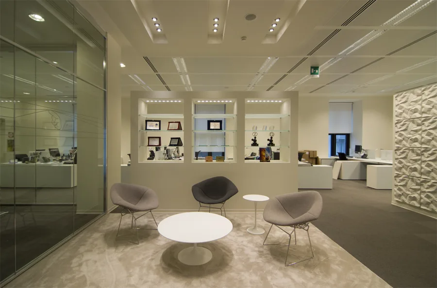 Level 3 executive lounge with Disney awards and trophies in illuminated display niches, Saarinen Executive chairs, and wood-framed views