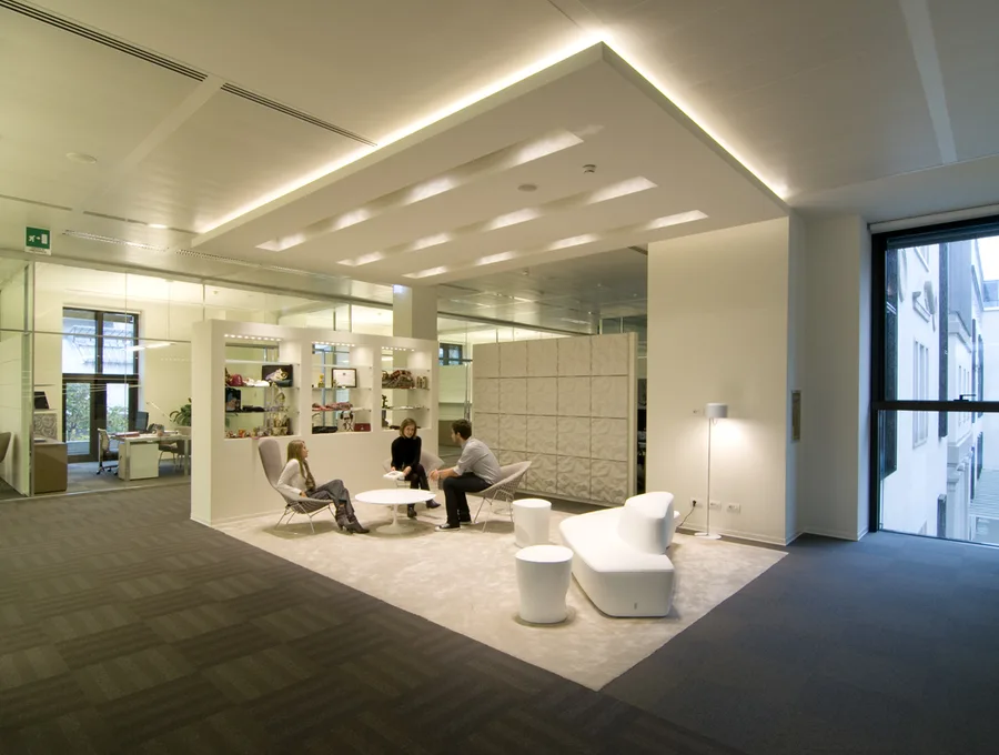 Level 3 executive lounge in use with employees, Moroso Saruyama Island seating, and Artemide Skydro pendants in warm white glow