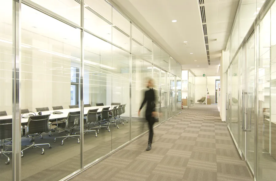 Level 3 corridor with motion-blurred figure walking past glass-partitioned offices, capturing the dynamic rhythm of the executive floor