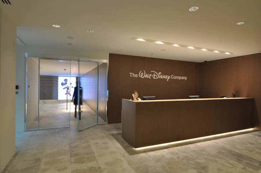 Panoramic view of the Disney headquarters interior, capturing the layered material language of Corian, Grey Oak, and Perle stone
