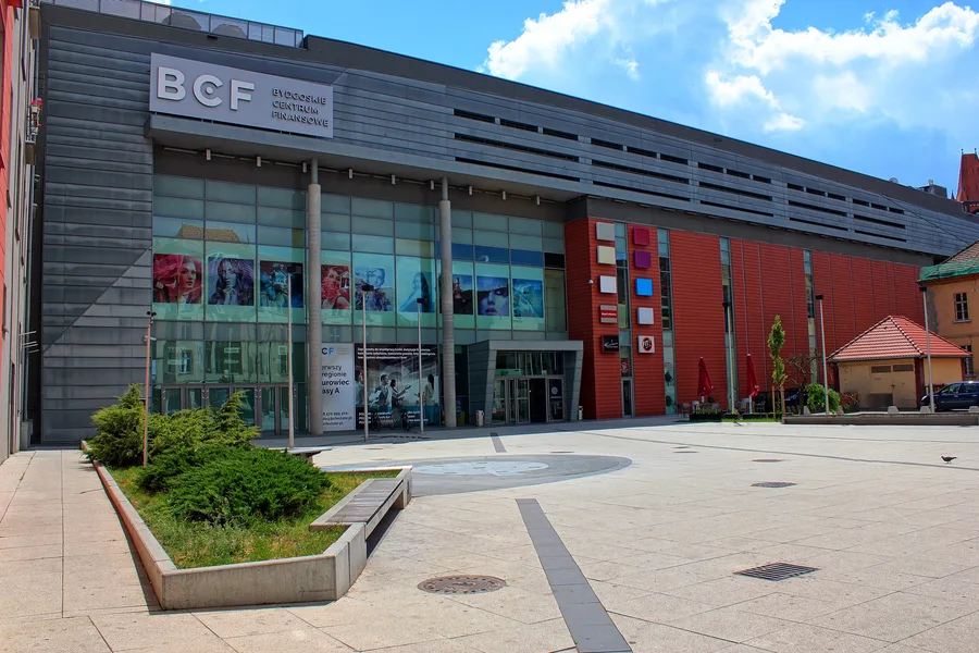 Interior: common area circulation space within Drukarnia Mall showing retail frontages, atrium void, and renovated finishes