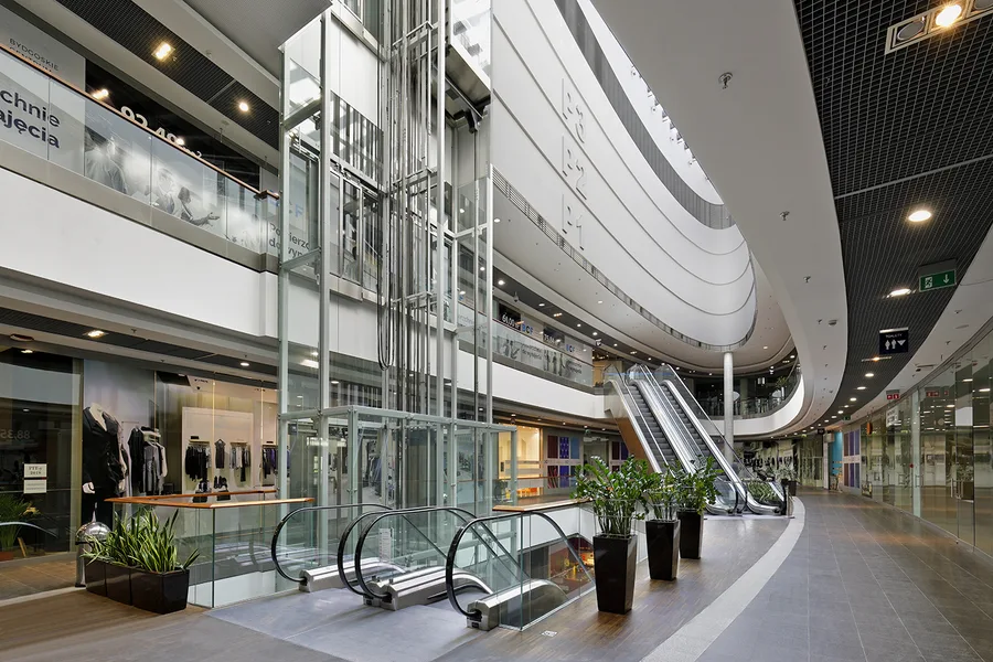 Exterior: professional photograph of Drukarnia Mall building elevation showing renovated commercial envelope and multi-facade signage programme