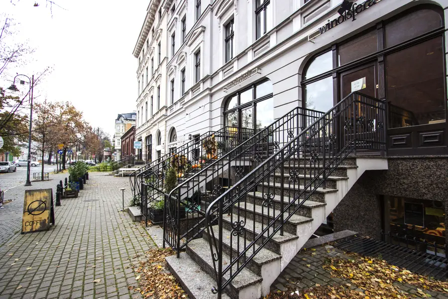 Autumn entrance detail with stone steps, iron railing, COFFEE sign board, fallen leaves, commercial ground floor signage