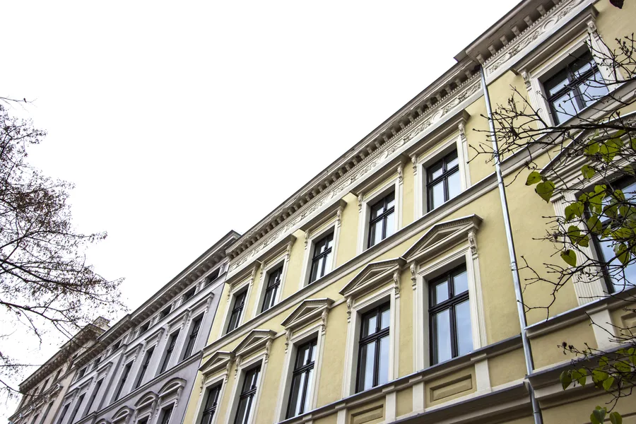 Yellow building upper floors with ornamental window details, cornice brackets, close-up architectural detail