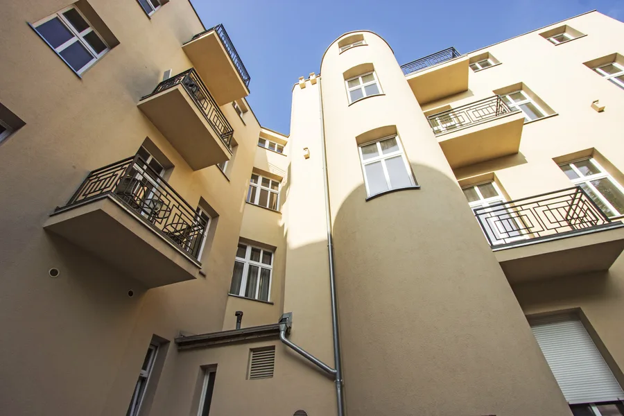 Courtyard looking up at staircase tower with balconies, blue sky, architectural geometry