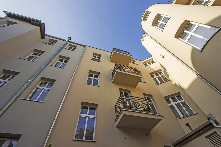 Courtyard looking up at wider angle showing balconies, satellite dish, drainpipes, architectural detail