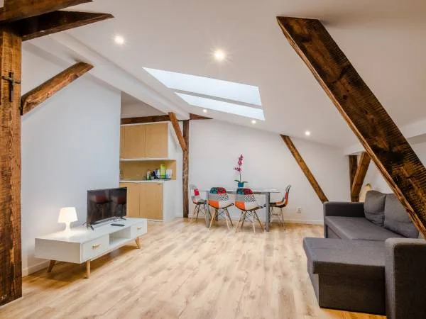 Attic apartment living room with exposed timber beams, skylight, Eames patchwork chairs, oak flooring, grey sofa