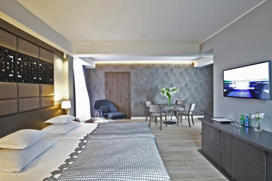 Luxury suite featuring Paluckie embroidery-inspired botanical perforated headboard, Womb chair, and warm oak herringbone flooring