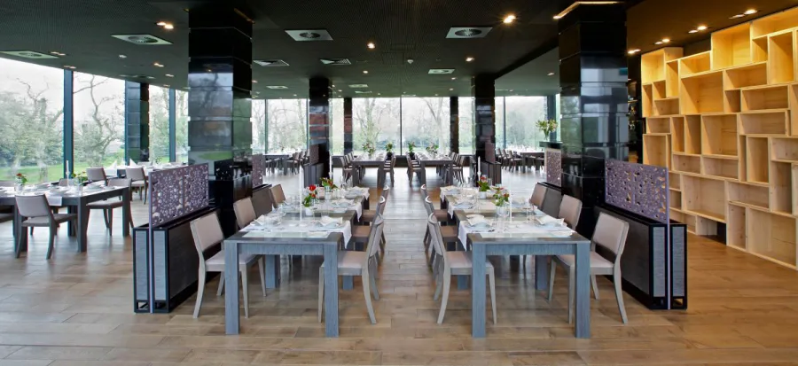 Restaurant Werbena with panoramic glazing on three sides, Cyclone dining tables, and views over the estate gardens
