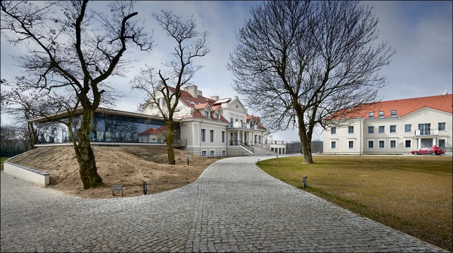Estate panorama showing three buildings, cobblestone path, and mature trees in the landscaped park