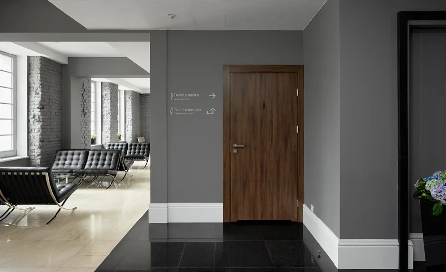 Corridor with wayfinding signage, Barcelona chairs, and exposed brick walls connecting hotel and restaurant zones
