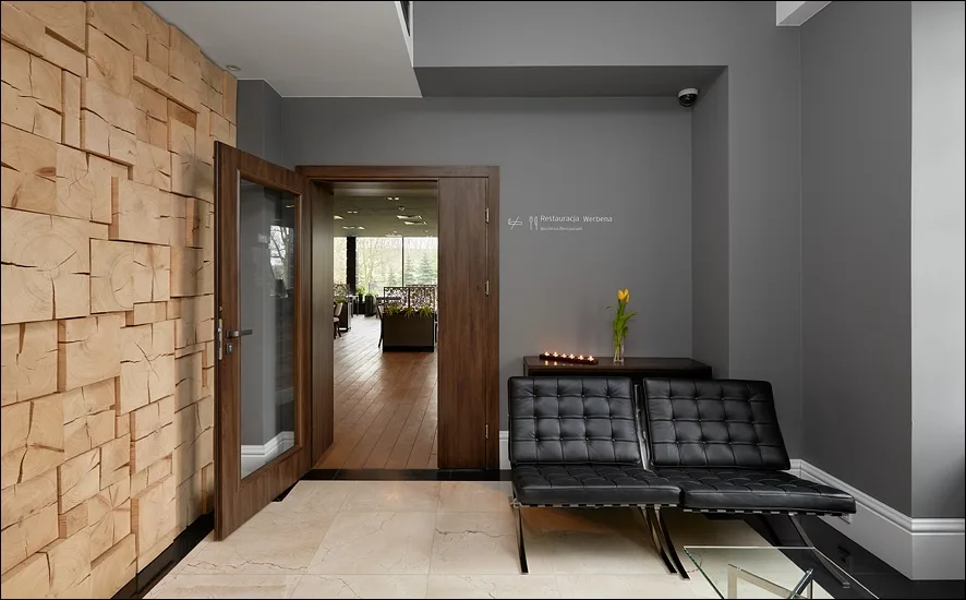 Lobby entrance with 3D wood block wall, Barcelona chairs, and Restaurant Werbena directional sign