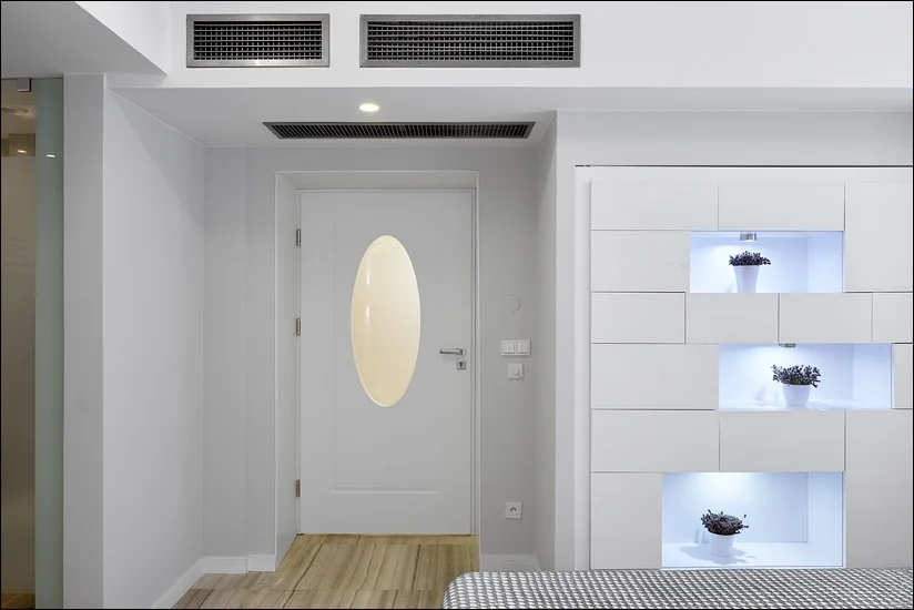 Spa corridor with white door featuring oval window, LED niches with lavender, and brick vault above