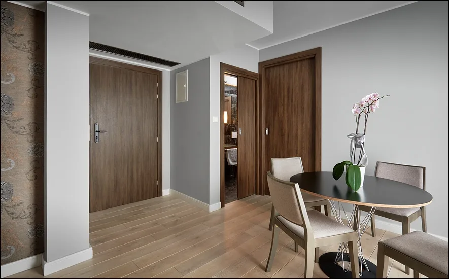 Suite dining area with walnut doors, round table, orchid centrepiece, and oak herringbone floor