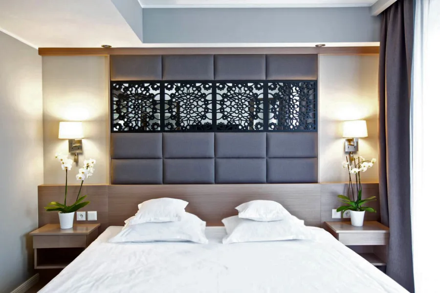 Bedroom close-up showing botanical perforated headboard detail with orchids and reading lamps