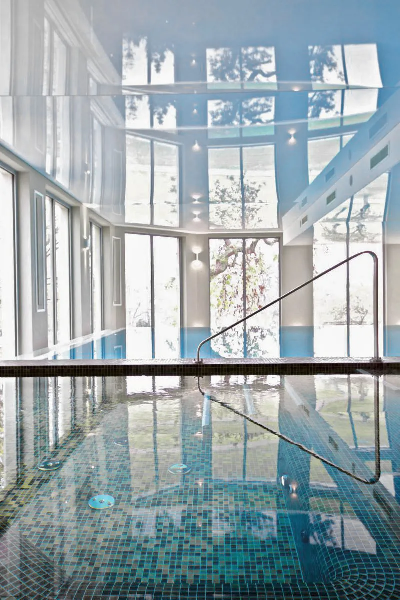 Infinity pool close-up showing mosaic detail and stretch ceiling reflection in turquoise water