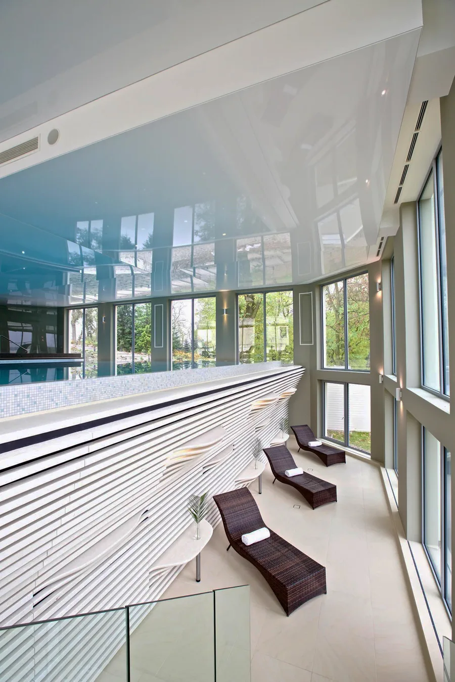 Pool relaxation level below with stretch ceiling, mosaic surfaces, and loungers on the lower spa tier