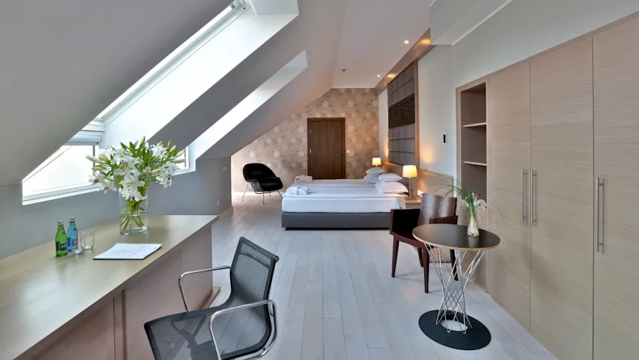 Attic suite with skylights, Womb chair, desk, botanical headboard, and oak floor under pitched ceiling