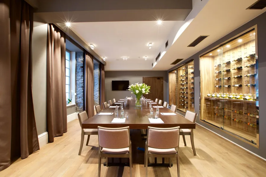Private dining room and wine room with walnut table, wine wall display, and exposed brick ceiling