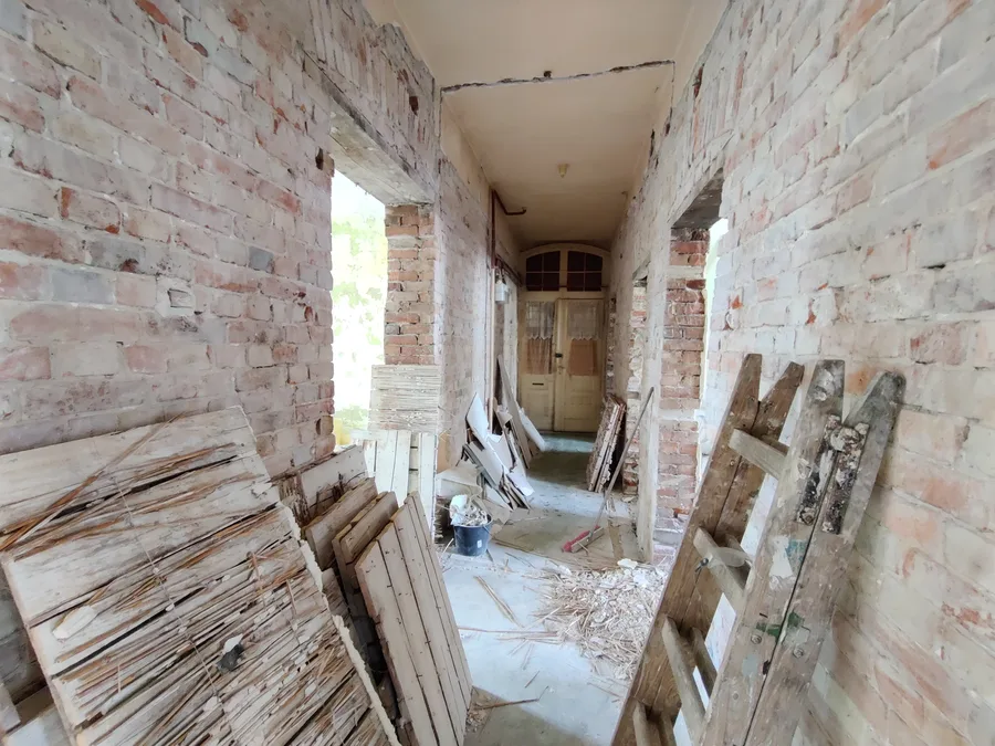 Before: existing kitchen area with old tile work, exposed wiring, removed fixtures, and masonry walls in strip-out condition during kamienica renovation