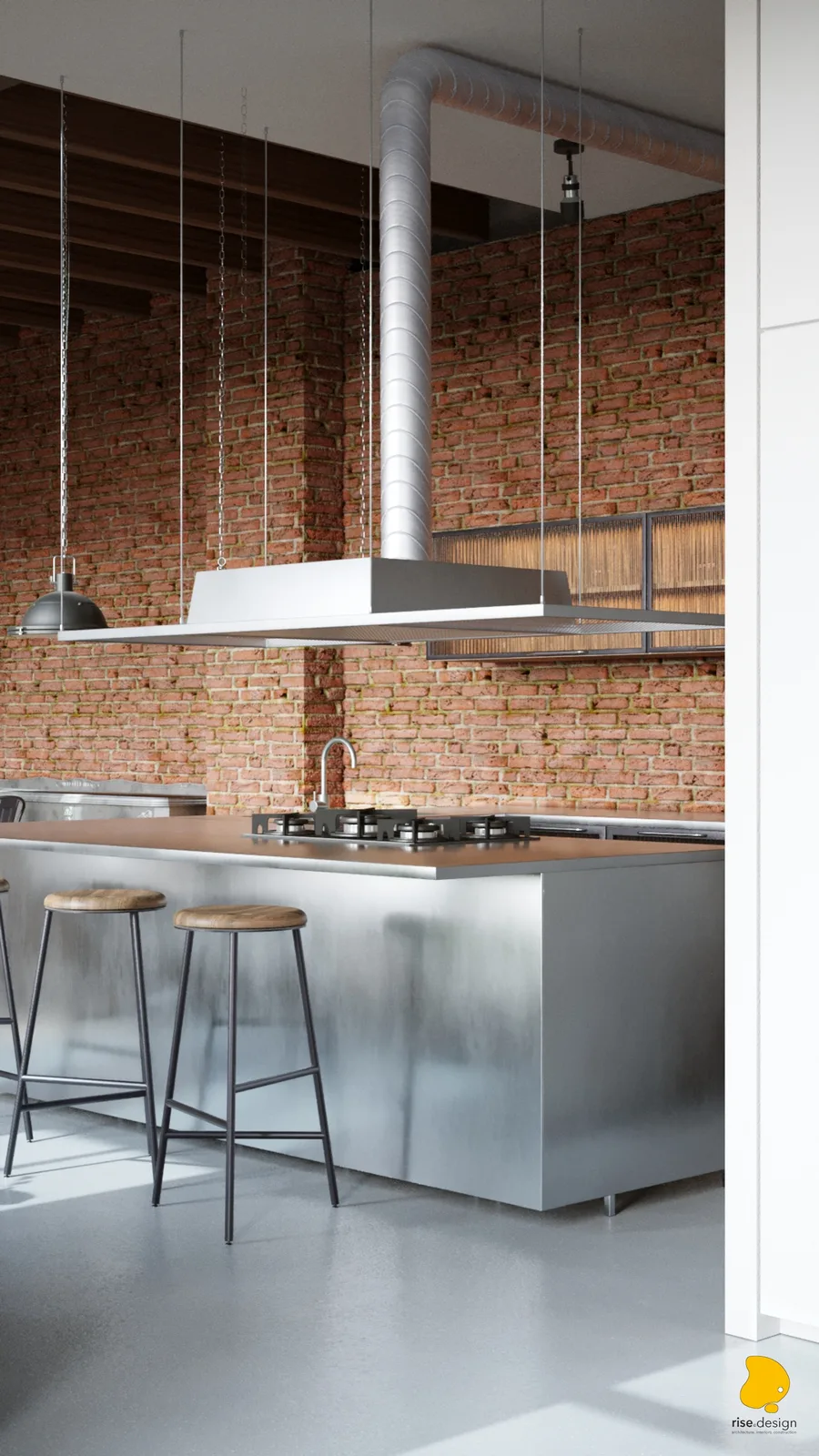 Stainless steel kitchen island with gas cooktop, bar stools, suspended range hood with spiral ventilation duct, and custom ribbed wood cabinets on brick wall