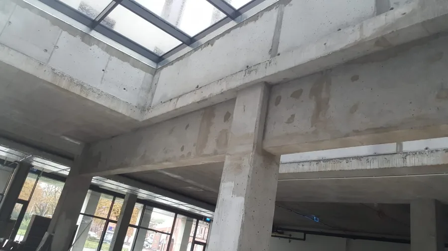 Documentary: design team on site during the October 2019 survey with person in tan coat pointing up at ceiling structure while inspecting insulated pipes and structural elements of the 1,200 square metre space