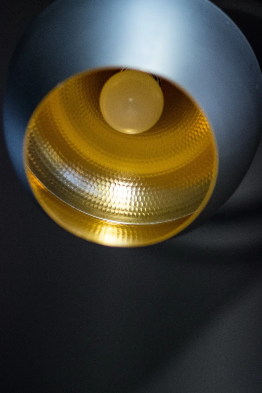 Detail: Tom Dixon Beat Fat pendant close-up from below showing hammered gold interior and warm glow
