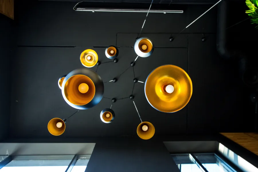 Detail: Tom Dixon Beat pendant cluster from below showing constellation of gold interiors against black ceiling and glass void