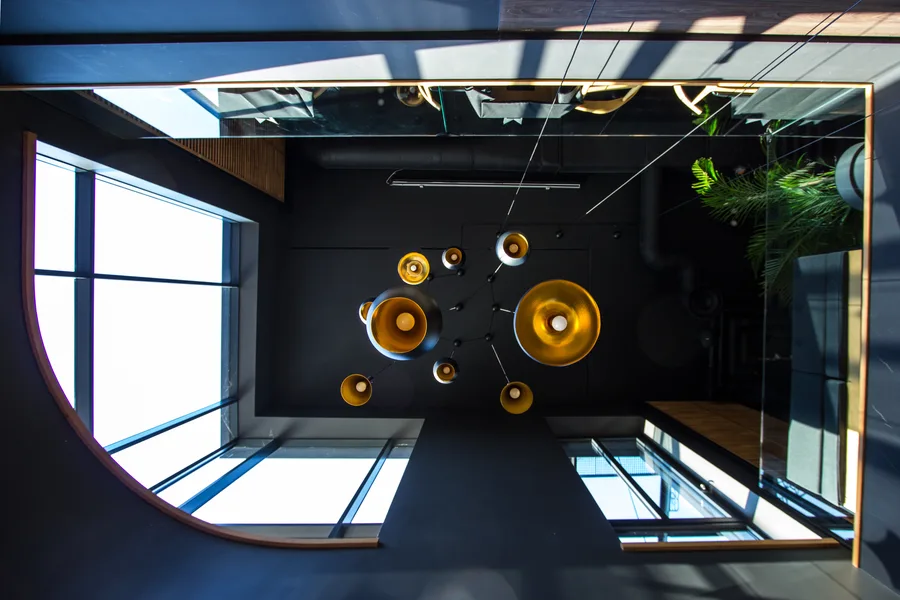 Interior: upper floor staircase void with Tom Dixon pendant cluster and venetian blinds looking toward curved glazing corner