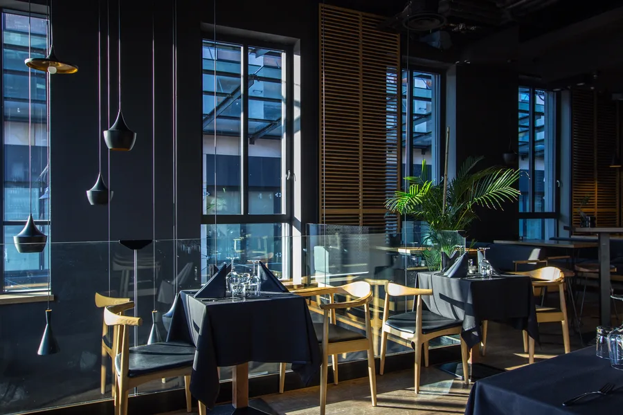 Interior: upper floor dining space long view along windows with venetian blinds, exposed ductwork, and hex tile wall at far end