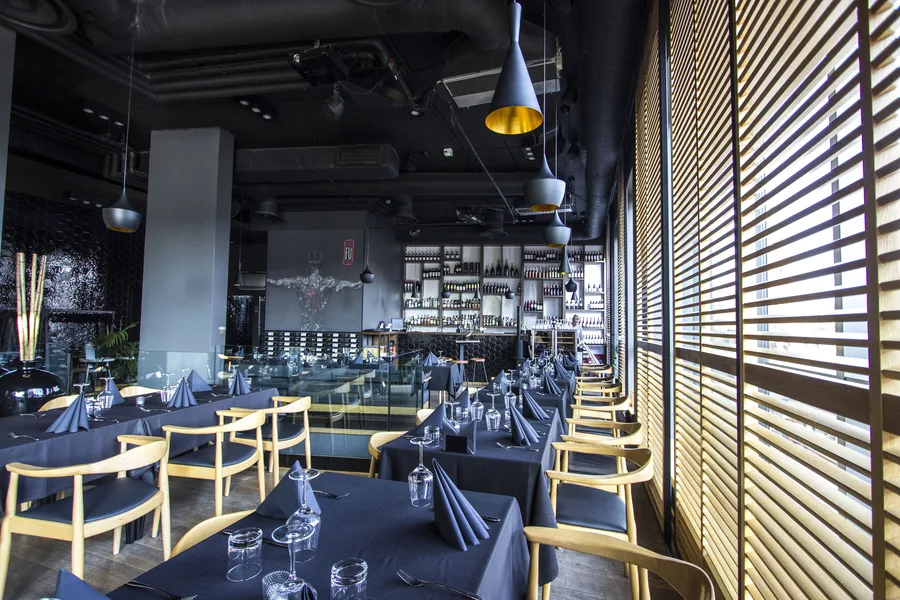 Interior: upper floor dining with warrior mural, wine wall, venetian blinds, and darker evening atmosphere