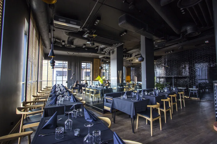 Interior: upper floor dining wide showing full space from hexagonal tiles to window wall, all tables set, evening lighting