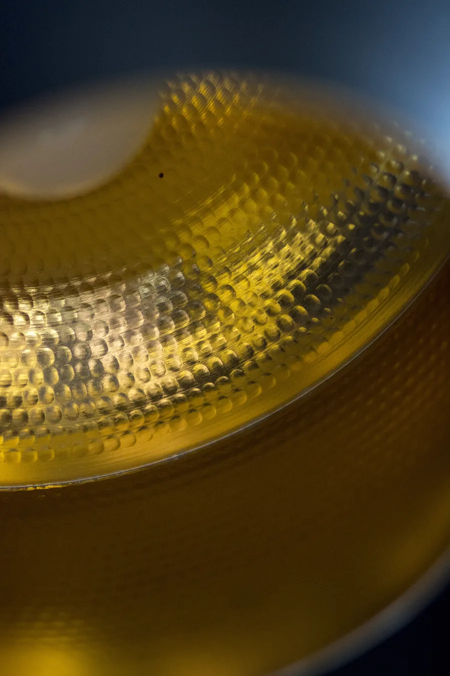 Detail: Tom Dixon Beat Fat pendant macro showing extreme close-up of hammered gold interior texture