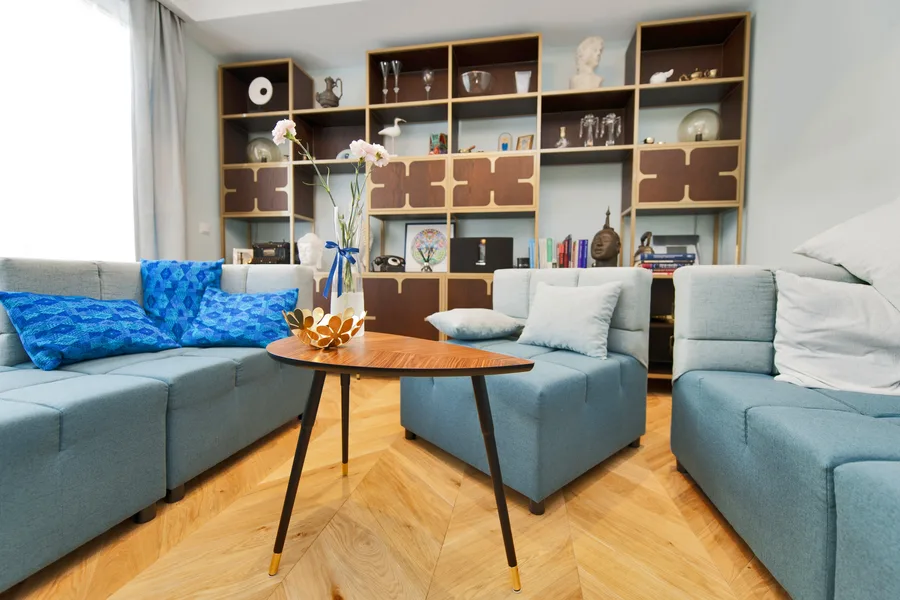 Living room wider angle showing bookshelving wall and sofa with more floor and spatial context visible, mid-century furniture arrangement