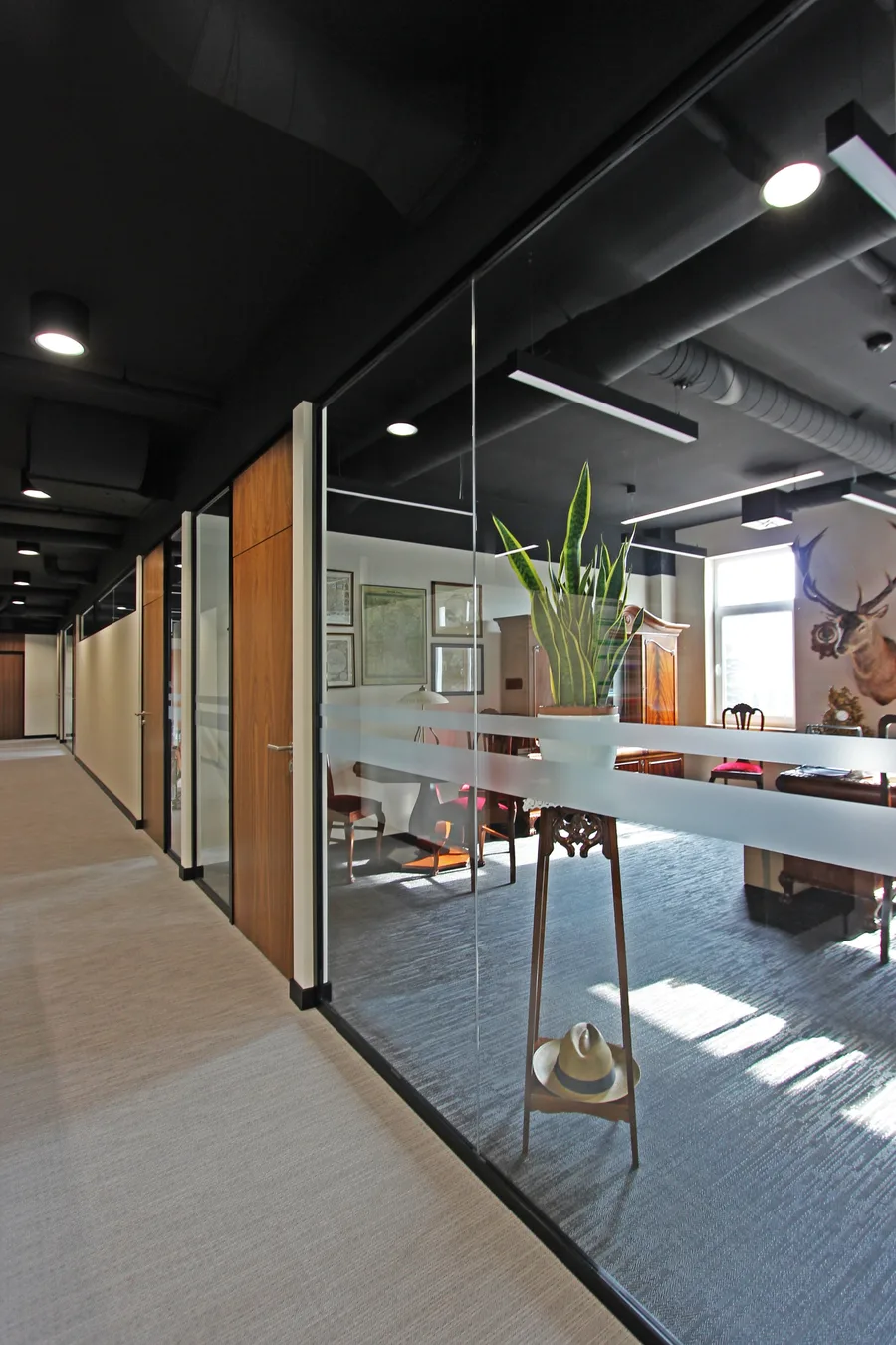 Interior: corridor view through glass partitions showing workspace depth and walnut veneer wall rhythm