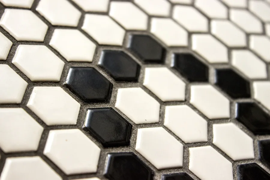 Detail: black hexagonal gloss tile mosaic macro close-up showing the koi-scale texture pattern that forms the signature ORSO NERO bar lettering