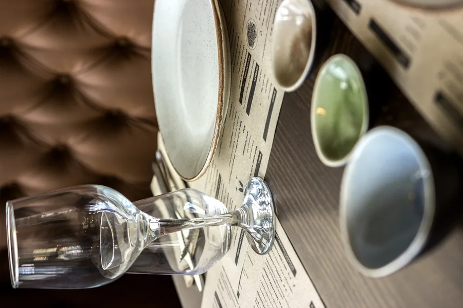 Speckled ceramic dinner plate with terracotta rim on oak dining table showing the artisan tableware selection