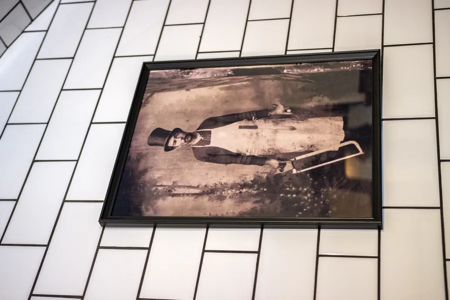 Vintage butcher portrait print in black frame on reclaimed timber wall within the curated Italian art programme