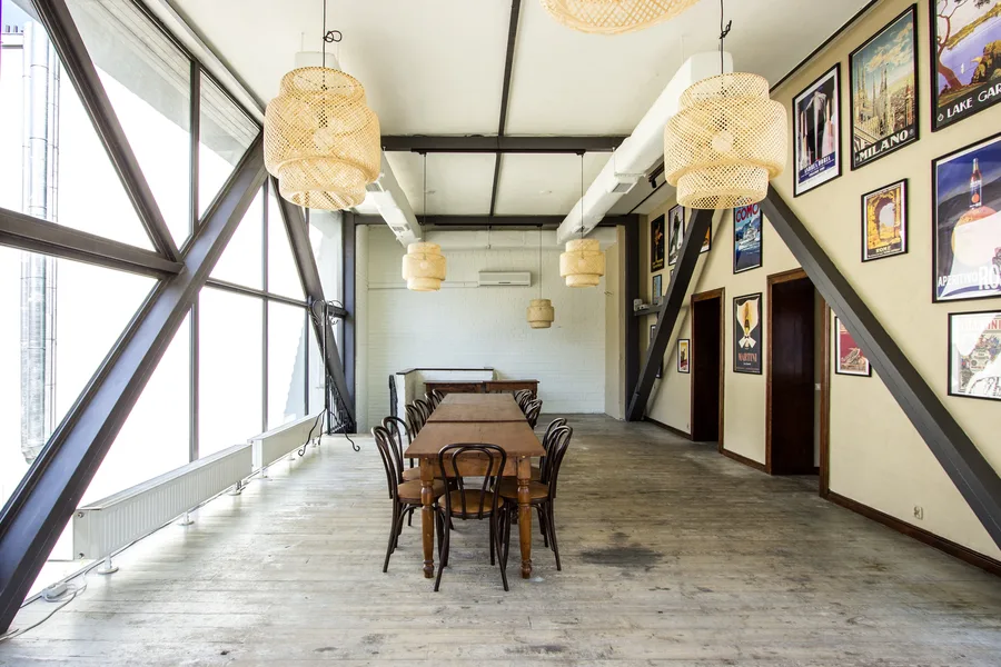 Ground floor showing poured microcement curved steps, reclaimed timber columns, and wrought iron balustrade connecting the two dining levels