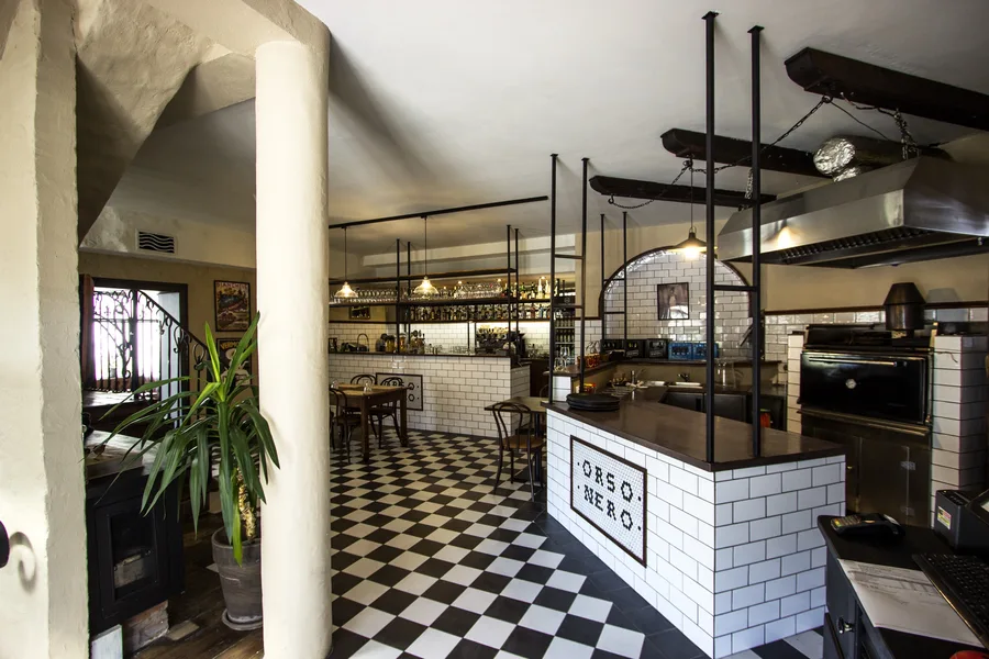 Bar seen from the entrance showing the full ground floor atmosphere with hexagonal tile counter, pendant lighting, and warm timber ceiling